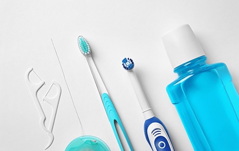 Toothbrushes, floss, and mouthwash on a white background