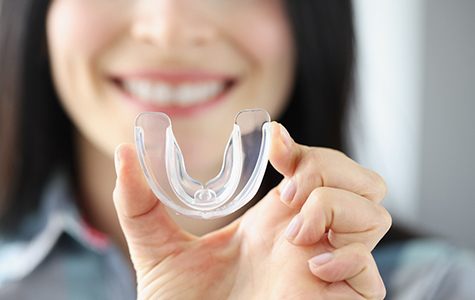 Woman holding up a clear mouthguard